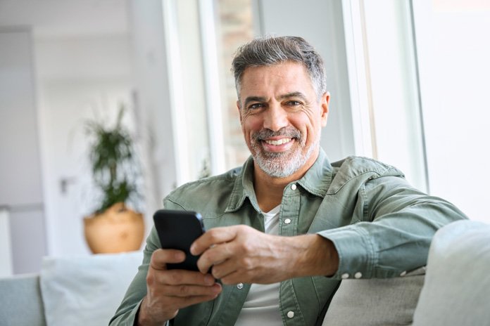 Homem maduro usando o celular em casa